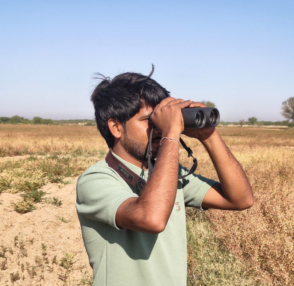 Chandraprakash looking out for lesser floricans through the binoculars.